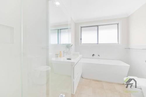 a white bathroom with a tub and a sink at Vivid House in Marsden Park in Marsden Park