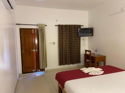 a bedroom with a bed and a table and a window at Dove cottage in Cherai Beach