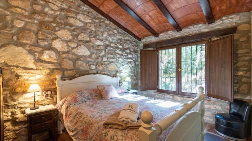 a bedroom with a bed in a stone wall at Molino Higueral Villanueva del Trabuco by Ruralidays in Villanueva del Trabuco