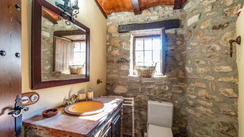 a stone bathroom with a sink and a mirror at Molino Higueral Villanueva del Trabuco by Ruralidays in Villanueva del Trabuco