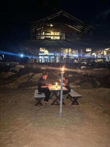 two men sitting at a table on the beach at night at Indika Beach Villa in Galle