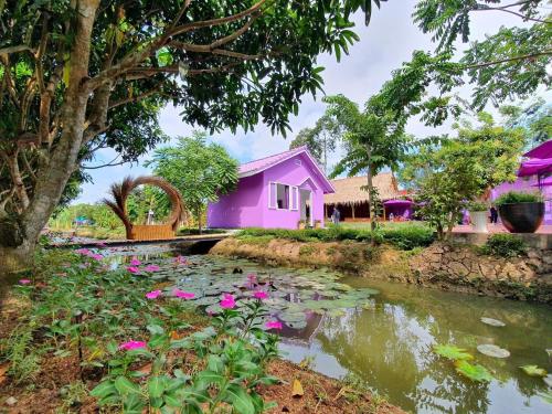 a pink house with a pond with pink flowers at Khách Sạn Nam Đô 1 in Can Tho