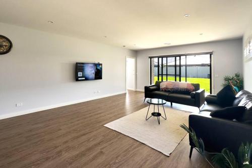a living room with a couch and a tv on a wall at Popular Luxury Villa Kialla Shepparton in Kialla