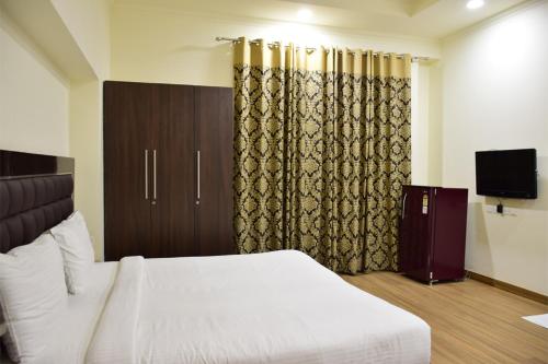 a hotel room with a bed and a television at When In Gurgaon - ARTEMIS HOSPITAL 1 Min Walk, FORTIS & MEDANTA 4 Mins Drive in Gurgaon