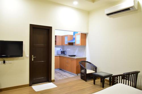 a room with a door and a kitchen with a table at When In Gurgaon - ARTEMIS HOSPITAL 1 Min Walk, FORTIS & MEDANTA 4 Mins Drive in Gurgaon