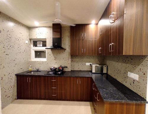 a kitchen with wooden cabinets and a counter top at When In Gurgaon - ARTEMIS HOSPITAL 1 Min Walk, FORTIS & MEDANTA 4 Mins Drive in Gurgaon