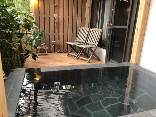 un patio con piscina y 2 sillas en una terraza en Hananoyado Fukuya, en Hakone