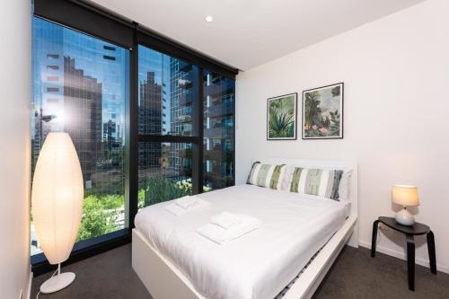 ein Schlafzimmer mit einem weißen Bett und einem großen Fenster in der Unterkunft 2-bed Apt w Pool Gym & Parking! Near Albert Park in Melbourne
