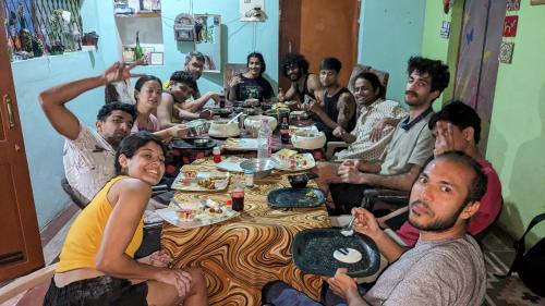 un grupo de personas sentadas alrededor de una mesa comiendo en Mani's place, en Hampi