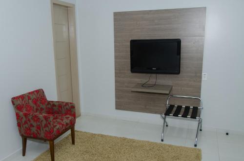 a room with a chair and a tv on a wall at Hotel Porto Madeira in Porto Velho