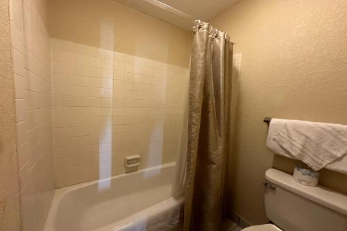 a bathroom with a shower and a tub and a toilet at River Valley Inn and Suites I-40 in Fort Smith