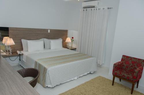a hotel room with a bed and a chair at Hotel Porto Madeira in Porto Velho