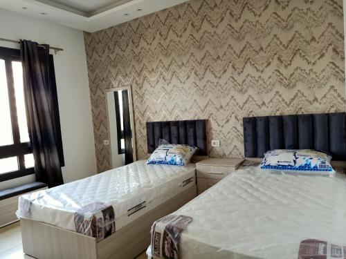 two twin beds in a bedroom with a wall at Fully furnished - 80 mt in Celia compound in new administrative city in Cairo