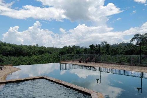 uma piscina com uma mesa de piquenique e nuvens no céu em The Apartment at Santubong em Kuching