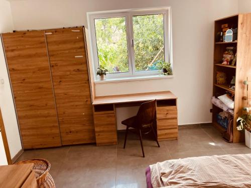 1 dormitorio con escritorio de madera y ventana en Pokoj v rodinném domě Severní en České Budějovice