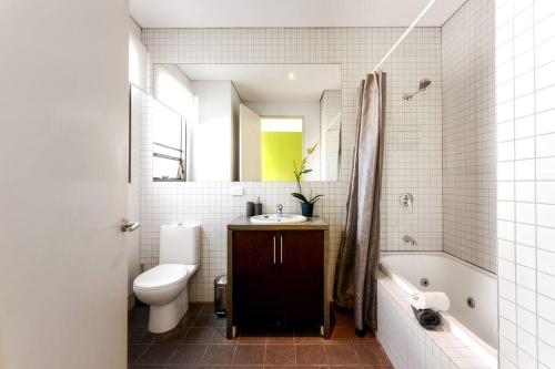 Un baño con lavabo, inodoro y bañera. en TWO FIVE ZERO RICHMOND four bedroom cityviews lockup garage, en Melbourne
