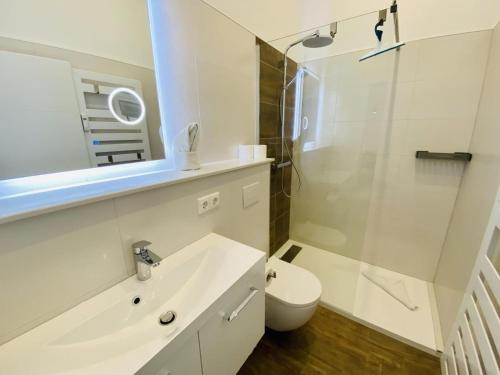 ein weißes Bad mit einem WC und einem Waschbecken in der Unterkunft Berringer Aal, an der Promenade in Warnemünde