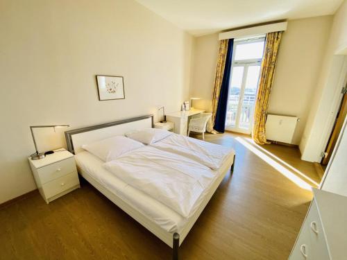 1 dormitorio con cama blanca y ventana grande en Berringer, Anker, direkt an der Promenade, en Warnemünde