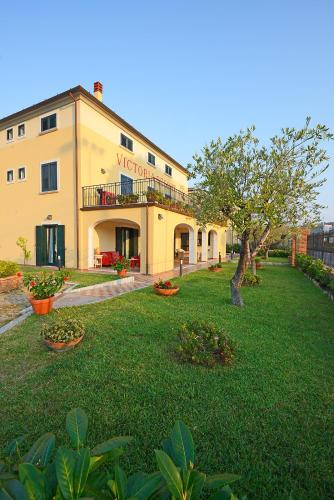 a large yellow building with a yard with a tree at Victoria Resort in Ascea