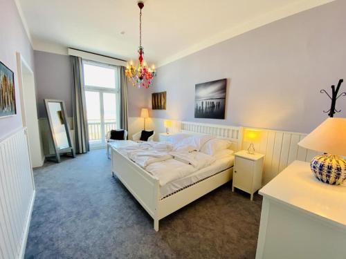 a bedroom with a large white bed and a chandelier at Berringer, Backbord, direkt an der Promenade in Warnemünde