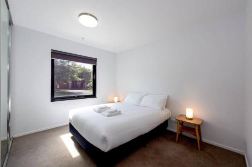 Habitación blanca con cama y ventana en Cozy 1Bed Unit in leafy Carlton - 10 mins from CBD, en Melbourne