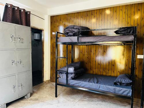 a room with three bunk beds in a wooden wall at Adinova in Kasol