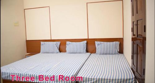 ein Bett mit zwei blauen und weißen gestreiften Kissen in der Unterkunft MOHAN'S RESIDENCY in Madurai