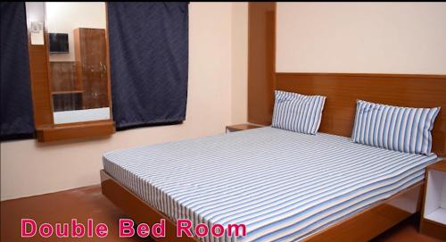 Schlafzimmer mit einem Bett mit blauen und weißen Streifen in der Unterkunft MOHAN'S RESIDENCY in Madurai