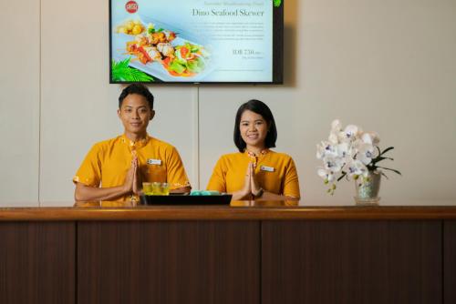 a man and a woman sitting at a reception desk at Banyu Biru Villa in Lagoi