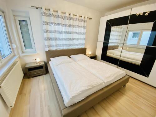 sypialnia z dużym białym łóżkiem i lustrem w obiekcie Daisy w mieście Warnemünde