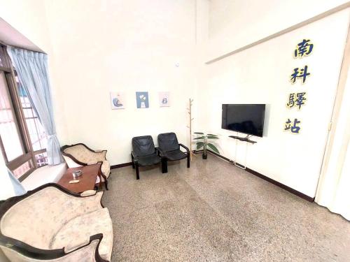 uma sala de estar com cadeiras e uma televisão num quarto em 南科驛站 em Xinshi