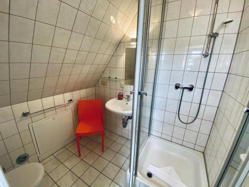 een badkamer met een douche en een rode stoel bij Ferienappartement Dicht Dran, direkt am Alten Strom in Warnemünde