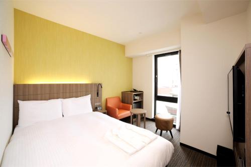 um quarto de hotel com uma cama e uma cadeira em Hotel Nets Sapporo em Sapporo