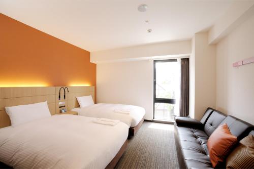 um quarto de hotel com duas camas e um sofá em Hotel Nets Sapporo em Sapporo