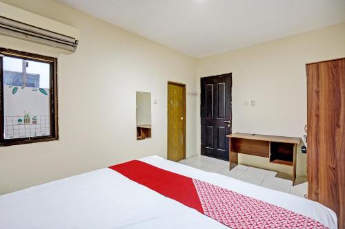 a bedroom with a bed and a desk in it at OYO Life 93111 Garden Homestay 2 Merlion in Lontar