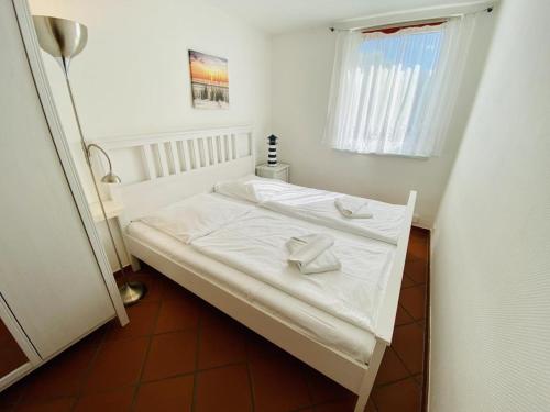 um quarto com uma cama com lençóis brancos e uma janela em Ferienhaus Lotse em Warnemünde