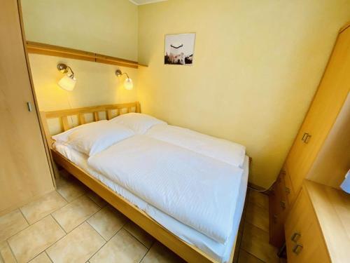 Schlafzimmer mit einem Bett mit weißer Bettwäsche und Beleuchtung in der Unterkunft Ferienhaus Schotstek in Warnemünde