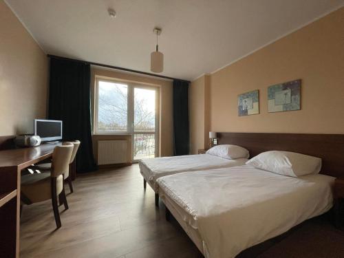 コウォブジェクにあるMotel Pieprzykのベッド2台、デスク、窓が備わるホテルルームです。
