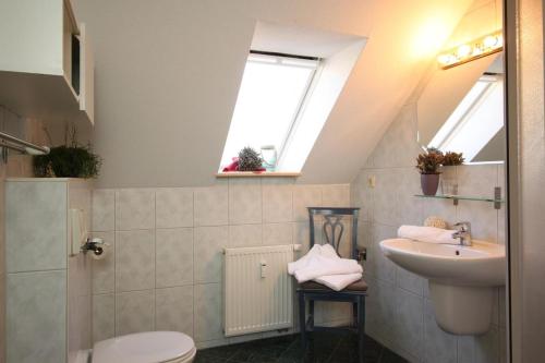 ein Bad mit einem Waschbecken, einem WC und Fenstern in der Unterkunft Ferienhaus am Yachthafen, Duenenzauber in Warnemünde