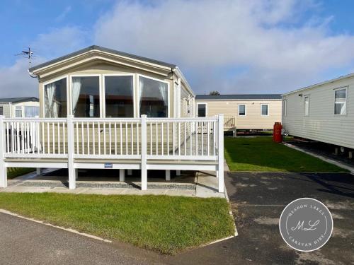 a white screened in porch in a yard at Palm Grove 132 - pet friendly, WiFi, central heating, close to shops and beach - Meadow Lakes Caravan & Lodge Hire in Chapel Saint Leonards