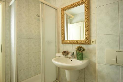 uma casa de banho com um lavatório e um chuveiro com um espelho. em Ferienhaus am Yachthafen, Seebrise em Warnemünde