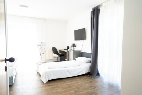 a white bedroom with a bed and a desk at AP Hotel Mannheim Viernheim in Viernheim