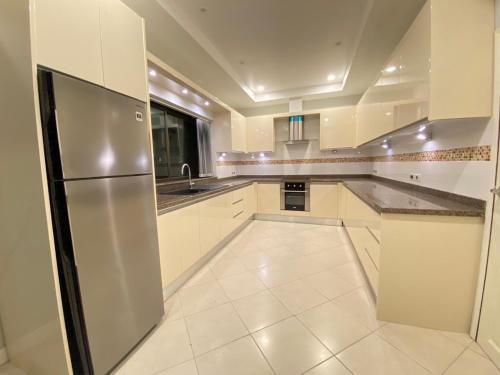 Una cocina con gabinetes blancos y un refrigerador de acero inoxidable. en Sunny2 Villa Pattaya, en Ban Huai Yai