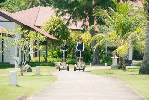 two people riding scooters down a sidewalk at Banyu Biru Villa in Lagoi