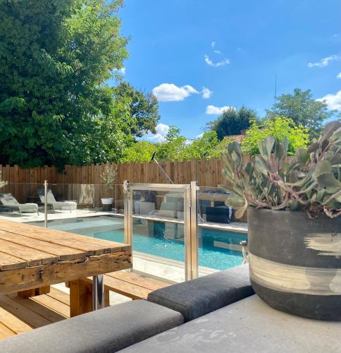une piscine avec une table en bois et une plante en pot dans l'établissement La villa Garonne avec piscine, à Toulouse