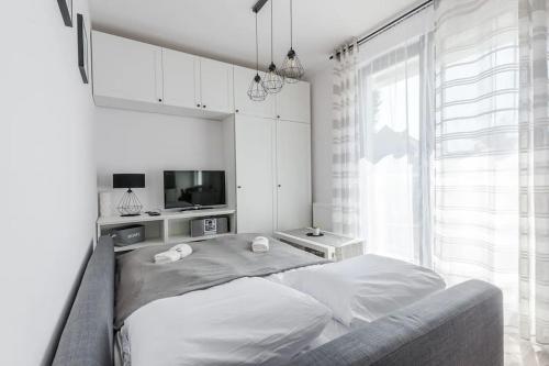 a white bedroom with a bed and a tv at Close-Golden Apartments Gdańsk&K2A in Gdańsk