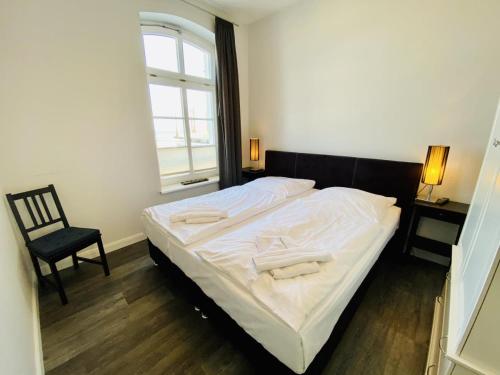 Bett in einem Zimmer mit einem Stuhl und einem Fenster in der Unterkunft Haus Jantzen/Arkona in Warnemünde