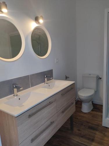 a bathroom with two sinks and a toilet with two mirrors at L'institution in Pont-Hébert