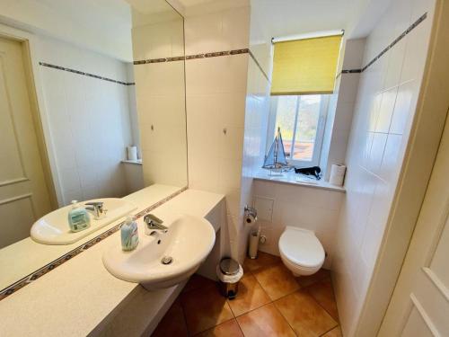 een badkamer met een wastafel, een toilet en een spiegel bij Horizont in Warnemünde