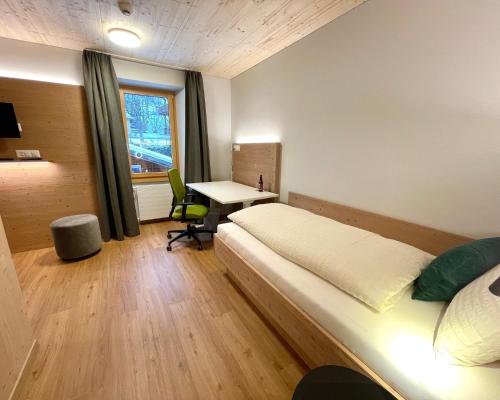 a bedroom with a bed and a desk and a window at Boutique und Bier Hotel des alpes in Fiesch